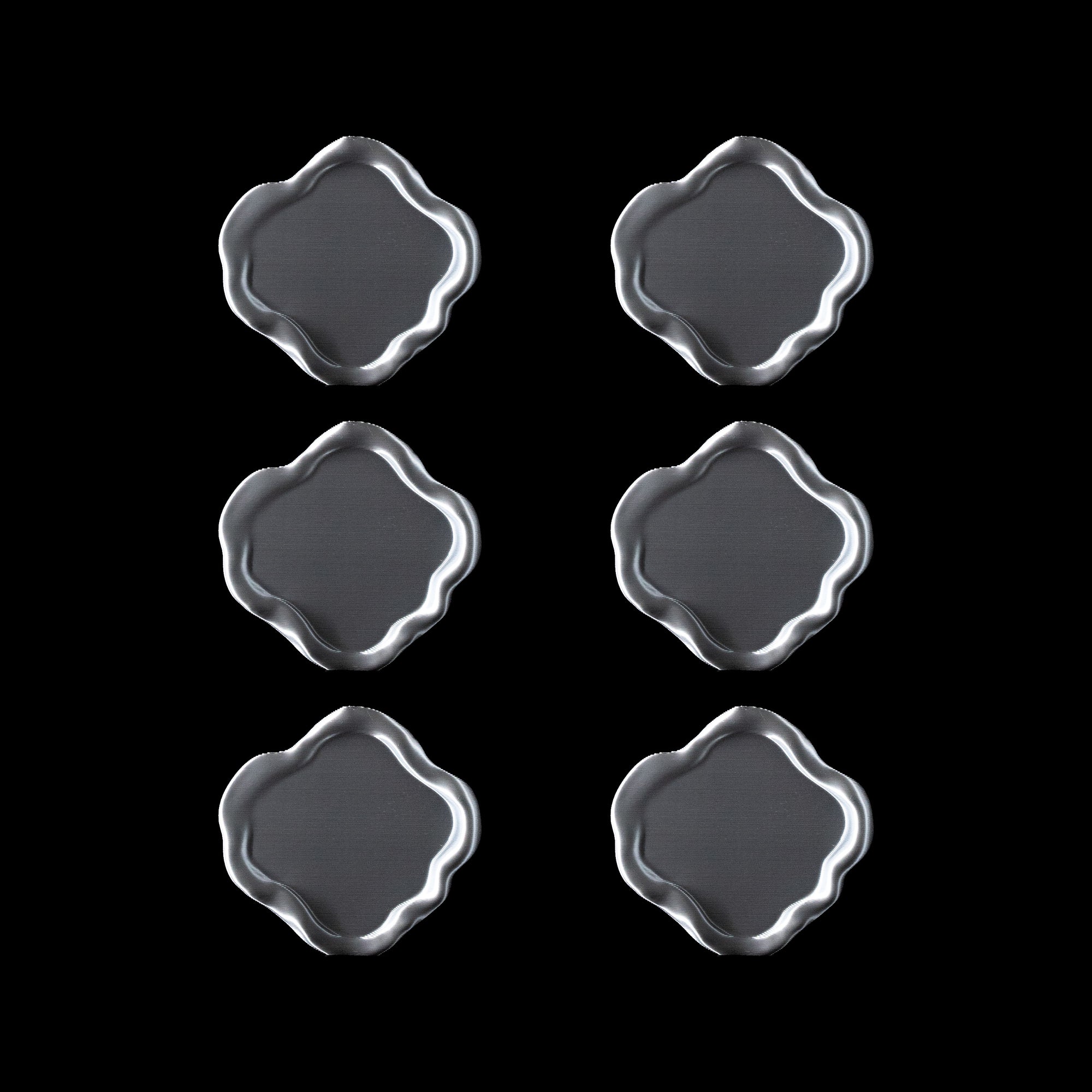 Lot de six dessous de verre Fuso en PLA chromé, disposés en grille sur fond noir