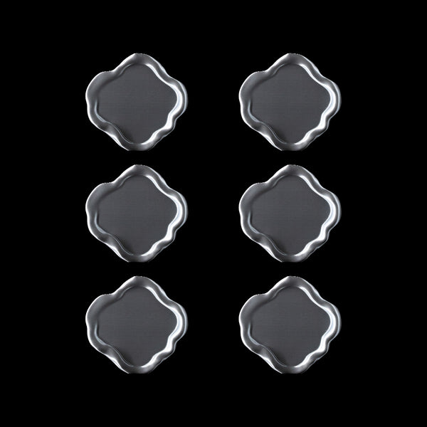 Lot de six dessous de verre Fuso en PLA chromé, disposés en grille sur fond noir