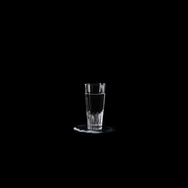 Dessous de verre Fuso en PLA chromé avec un verre d’eau, photographié sur fond noir
