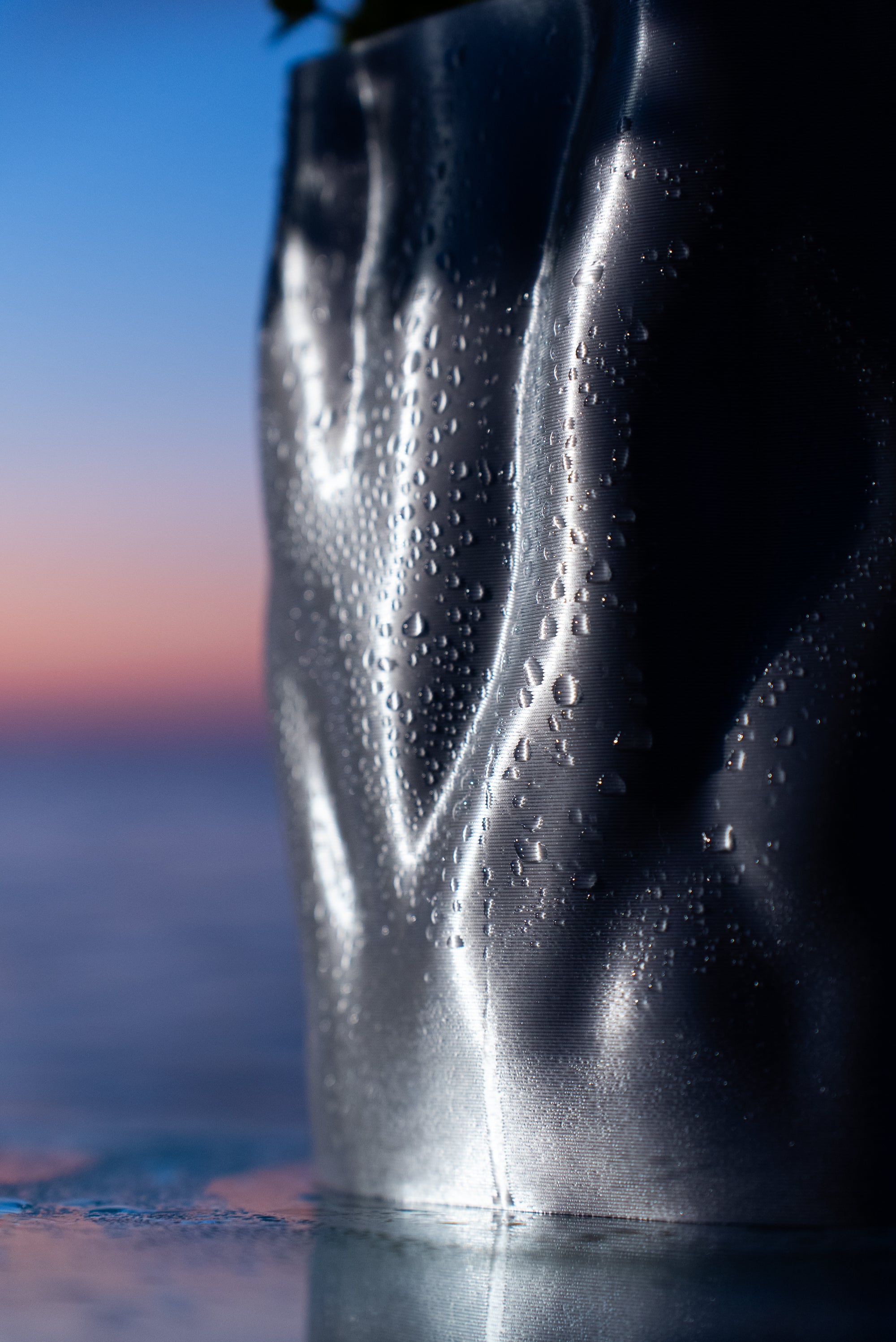 Vase Aura Aether sur table en verre au lever du soleil, collection Chrome Core S7DE Studio.