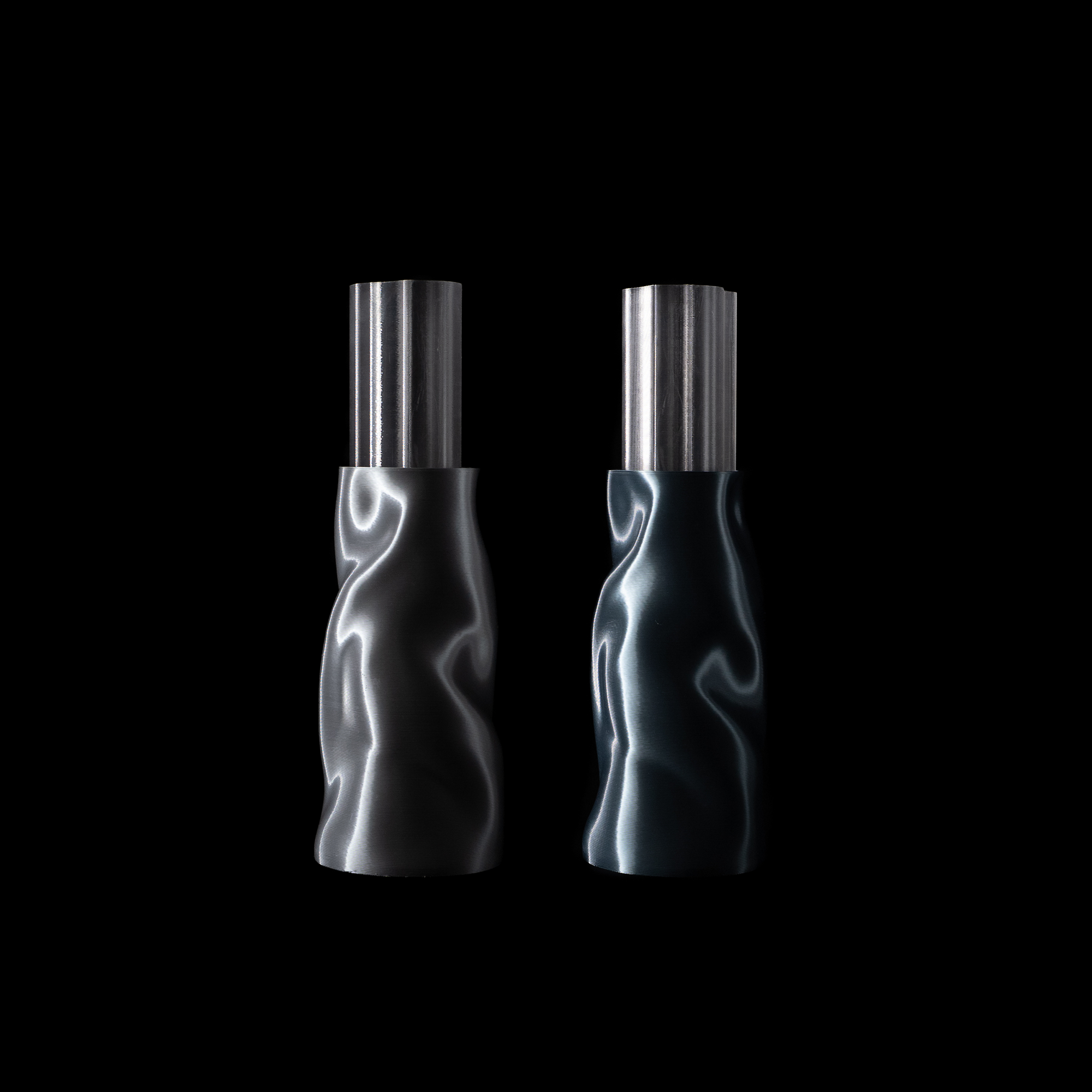 Vases Riflesso en coloris Chrome et Aether avec insert en PETG translucide, posés sur fond noir