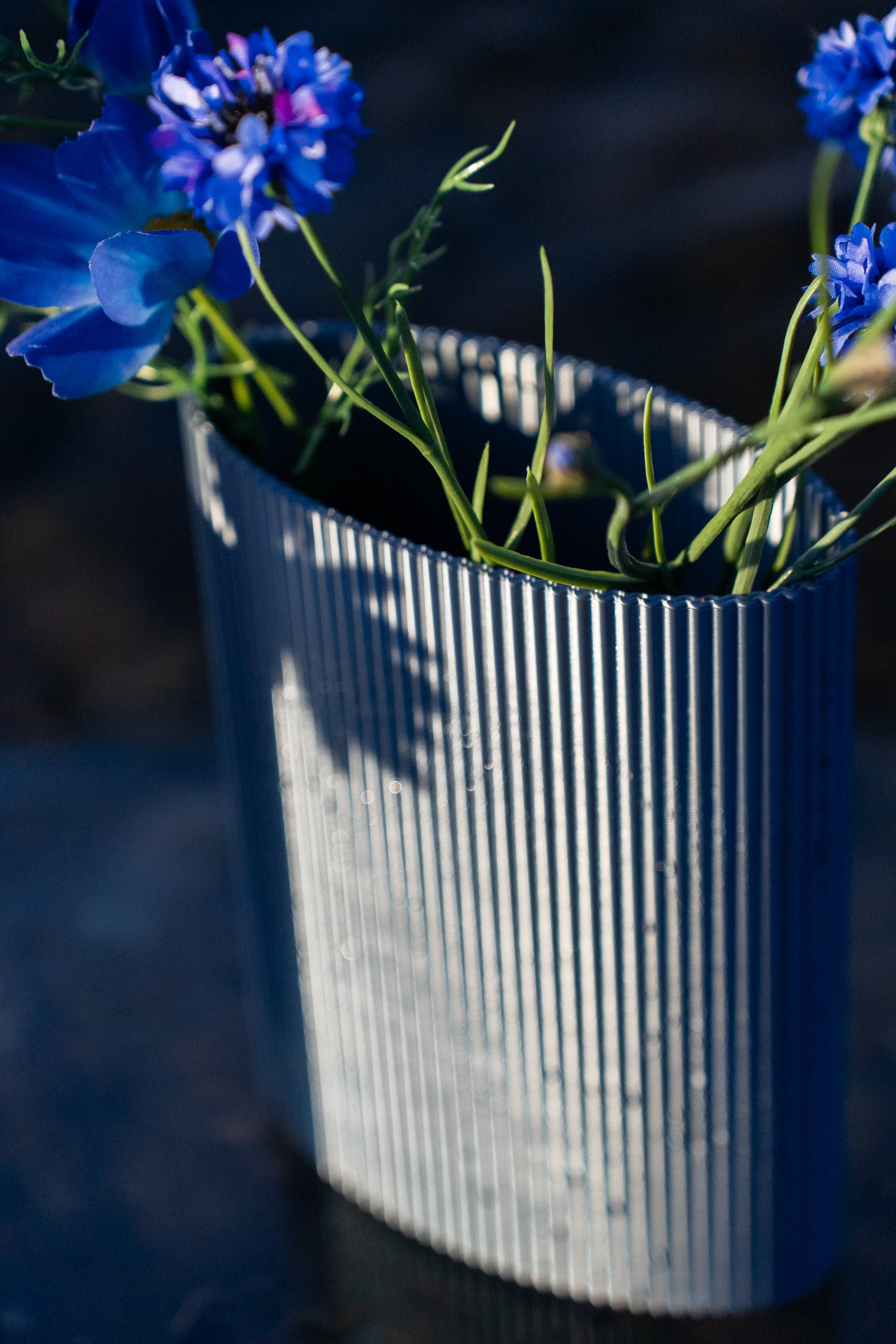 Vase Riga en PLA chromé, à stries verticales, garni de fleurs bleues au lever du soleil