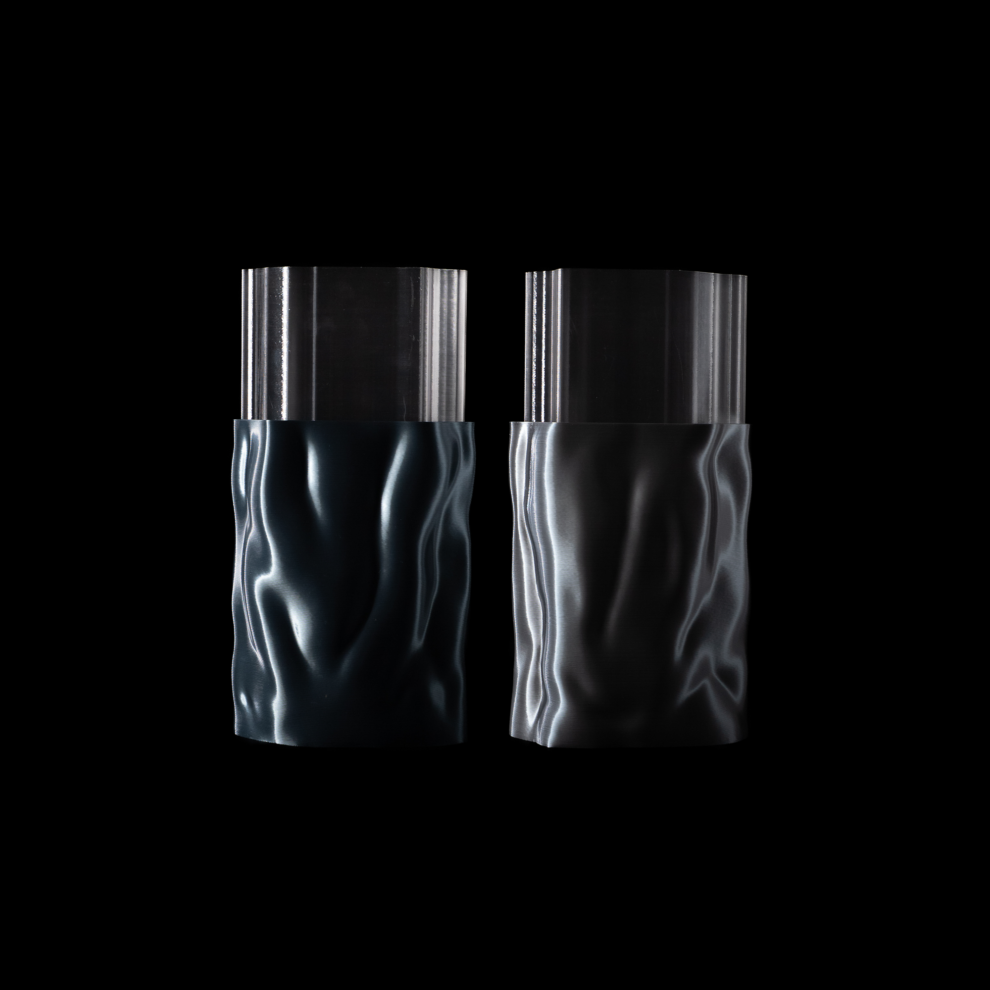 Vases Aura en coloris Chrome et Aether avec insert transparent, présentés côte à côte sur fond noir. Design fluide et reflets métalliques brillants.