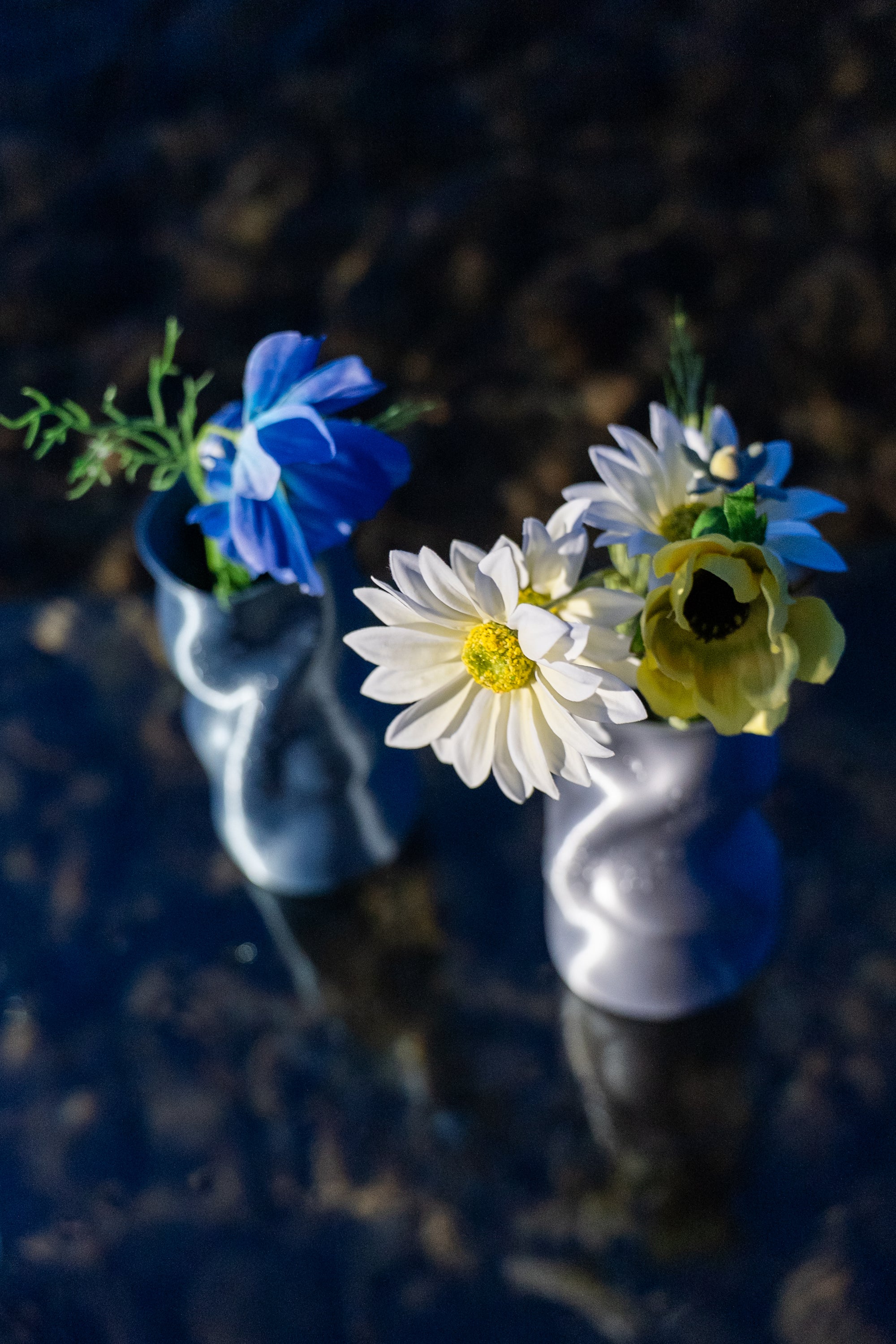 Vases Riflesso en Aether et Chrome remplis de fleurs, posés sur une table dans l’eau.